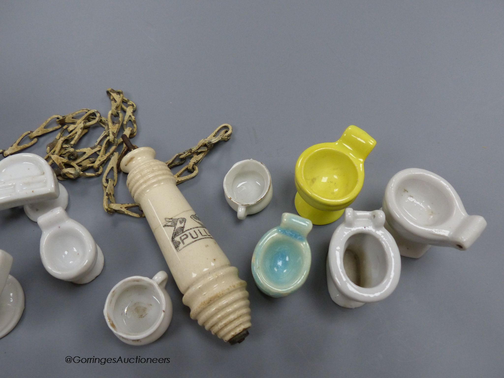 A group of various miniature models of toilets and a pull chain